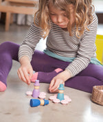 A close up of a child playing with the Grapat 12 Magos wooden peg dolls. These wooden toys are part of a wide range of open ended toys available at Babipur.  