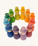 Grapat 12 Magos wooden peg dolls with top hats in a rainbow of 12 colours placed in a circle. These wooden toys are part of a wide range of open ended toys available at Babipur.  