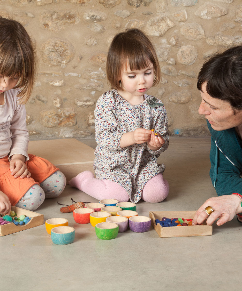 Two children and an adult playing with the Grapat 12 Rainbow Wooden Sorting Bowls. These Grapat bowls are part of a big range of open ended wooden toys available at Babipur. 