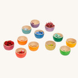 Grapat 12 Rainbow Wooden Sorting Bowls filled with loose parts and natural pieces in matching colours. These Grapat bowls are part of a big range of open ended wooden toys available at Babipur. 