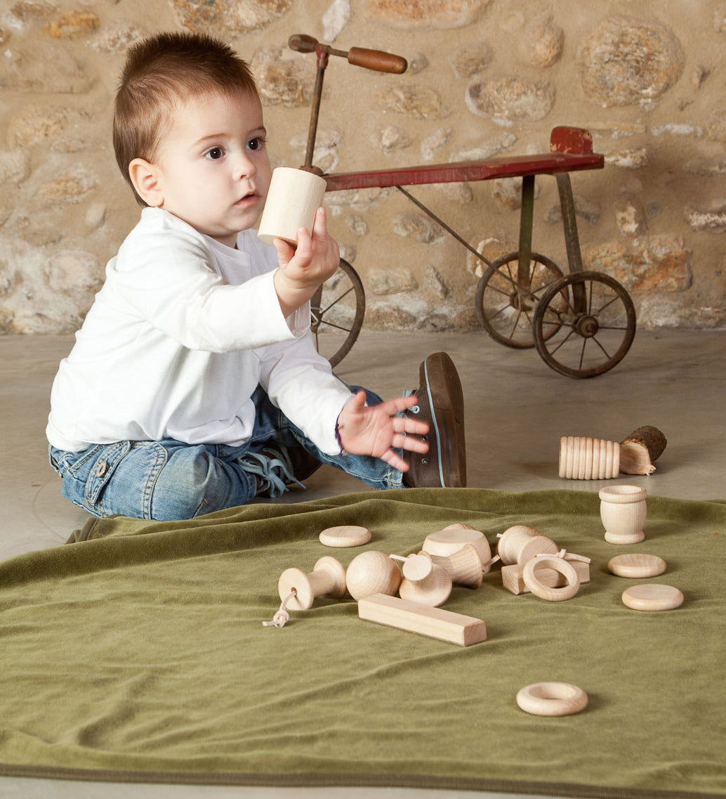 A child playing with the pieces from the Grapat 20 Element Treasure Basket. A mix of wooden toys for little hands to explore. These wooden toys are part of a wide range of open ended toys available at Babipur.  