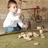 A child playing with the pieces from the Grapat 20 Element Treasure Basket. A mix of wooden toys for little hands to explore. These wooden toys are part of a wide range of open ended toys available at Babipur.  