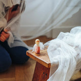 An angel wooden peg doll created from a box  from the Grapat 2026 advent calendar available at Babipur placed on a wooden stool in front of a child.