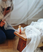 An angel wooden peg doll created from a box  from the Grapat 2026 advent calendar available at Babipur placed on a wooden stool in front of a child.