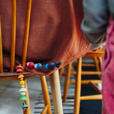 Close up of a child golding a string with colourful wooden beads  threaded onto it from one of the gifts included in the Grapat 2026 advent calendar available at Babipur.