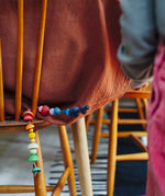 Close up of a child golding a string with colourful wooden beads  threaded onto it from one of the gifts included in the Grapat 2026 advent calendar available at Babipur.