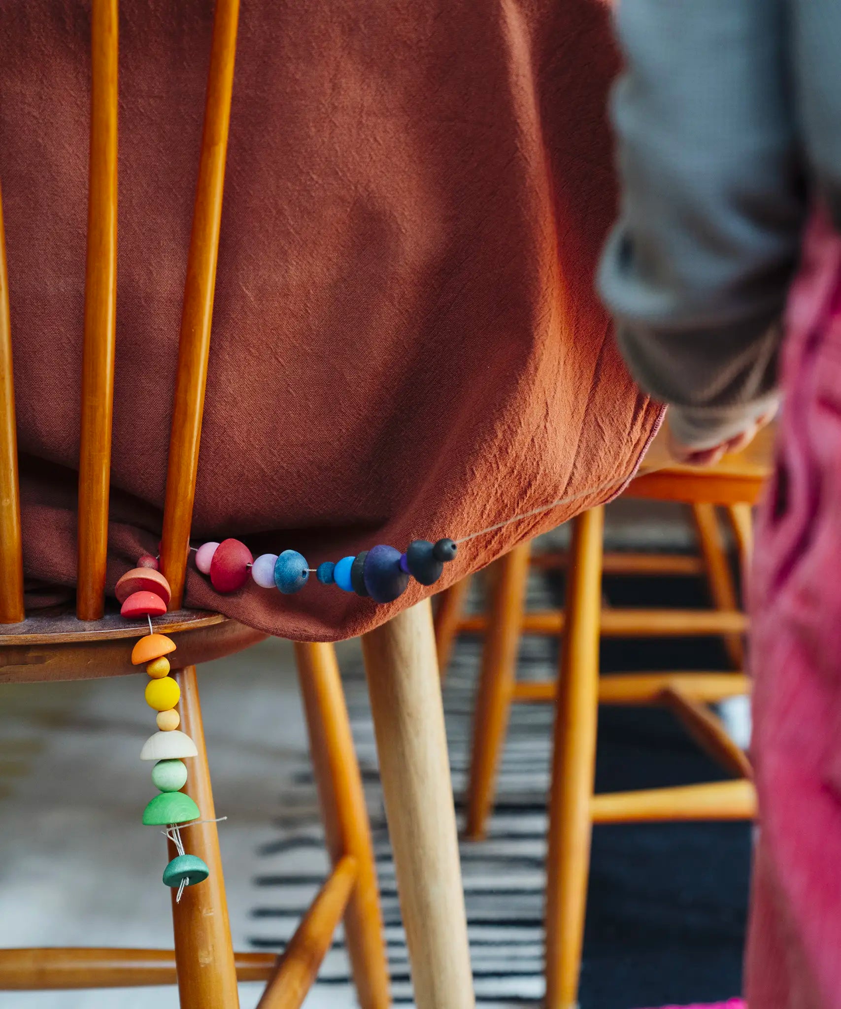Close up of a child golding a string with colourful wooden beads  threaded onto it from one of the gifts included in the Grapat 2026 advent calendar available at Babipur.