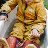 Child sitting in water playing with a small sail boat toy created using pieces from one of the gifts included in the Grapat 2026 advent calendar available at Babipur. 
