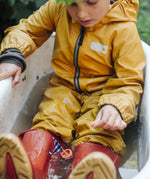 Child sitting in water playing with a small sail boat toy created using pieces from one of the gifts included in the Grapat 2026 advent calendar available at Babipur. 