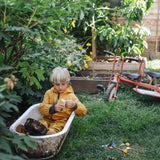 Child sitting in water playing with a small sail boat toy created using pieces from one of the gifts included in the Grapat 2026 advent calendar available at Babipur. 