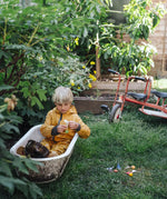 Child sitting in water playing with a small sail boat toy created using pieces from one of the gifts included in the Grapat 2026 advent calendar available at Babipur. 