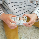 Close up of a child's hand opening a gift included in the Grapat 2026 advent calendar available at Babipur showing two wooden peg dolls inside.