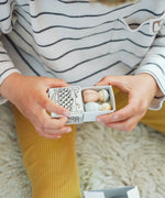 Close up of a child's hand opening a gift included in the Grapat 2026 advent calendar available at Babipur showing two wooden peg dolls inside.