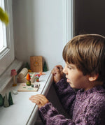 Child looking on at a set up of small wooden toys included in the Grapat 2026 advent calendar available at Babipur.