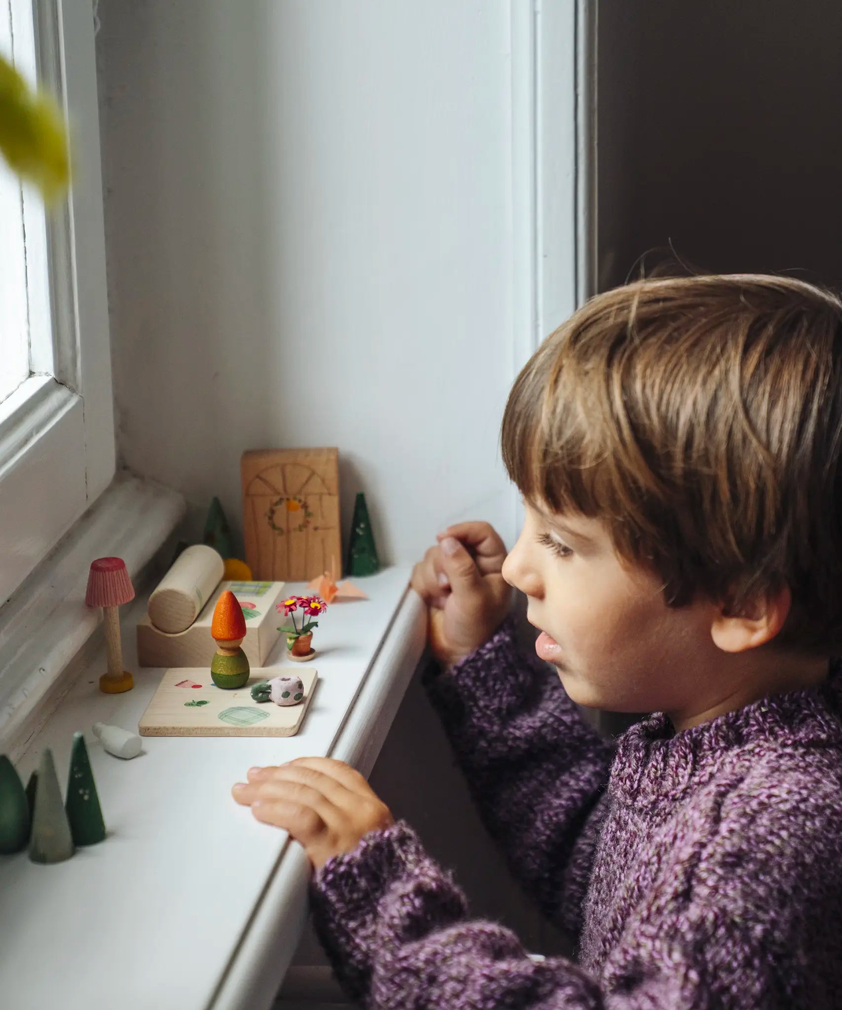 Child looking on at a set up of small wooden toys included in the Grapat 2026 advent calendar available at Babipur.