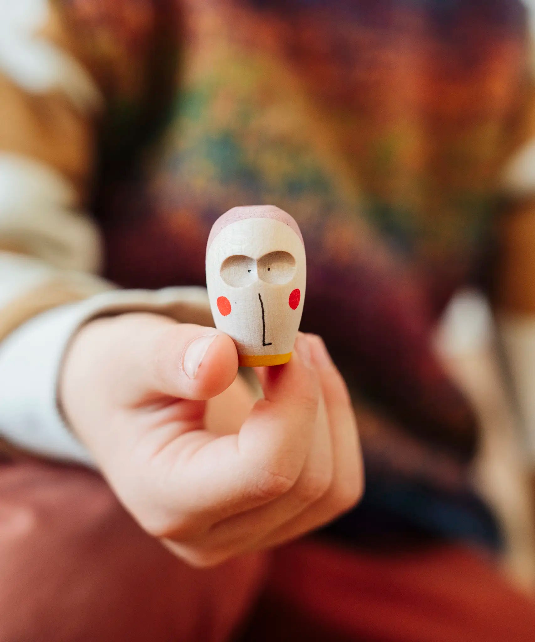 Close up of a wooden face piece in a child's hand from one of the gift boxes included in the Grapat 2026 advent calendar available at Babipur.