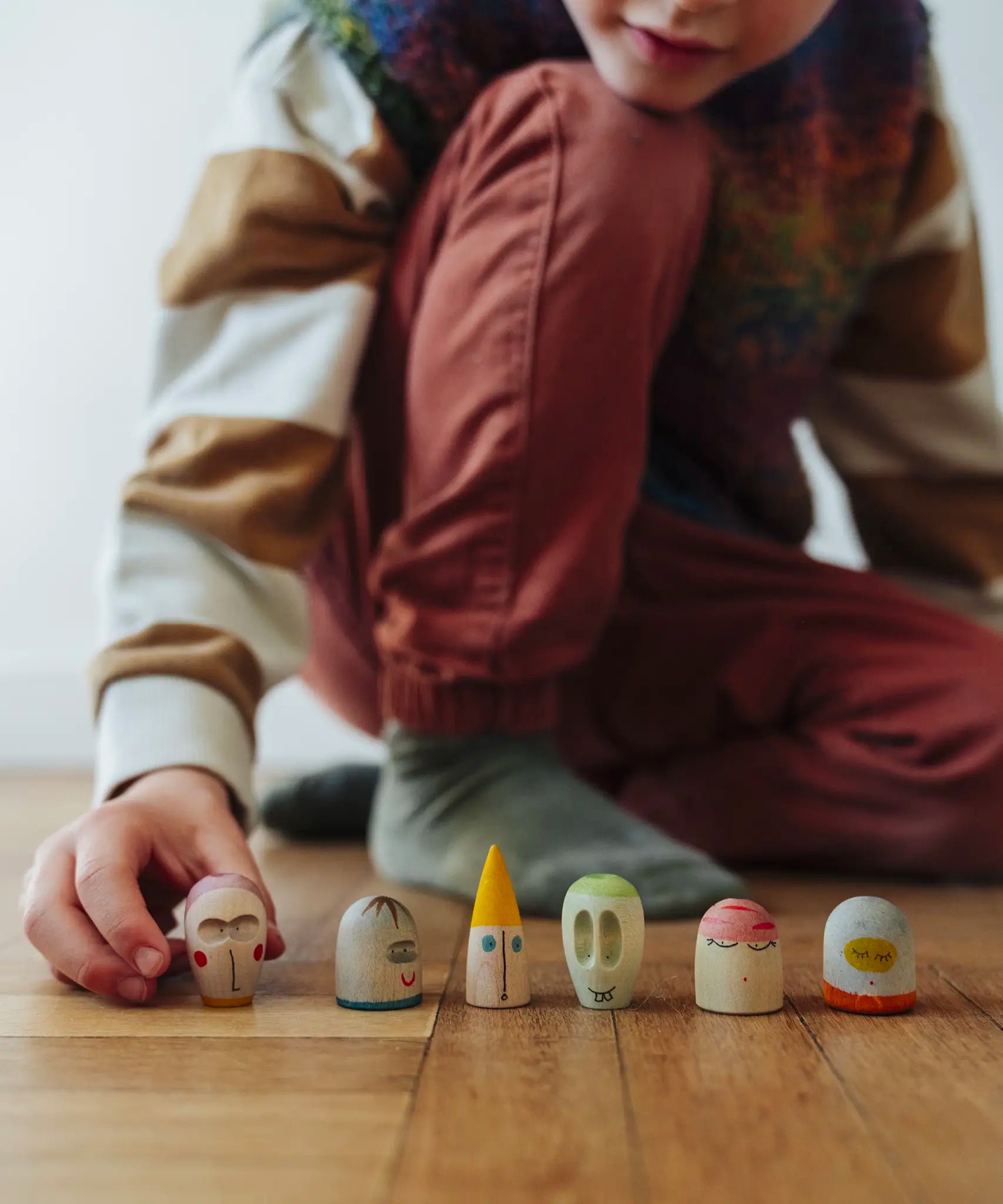 Child's hand lining up wooden face pieces  included in the Grapat 2026 advent calendar available at Babipur.