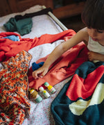 Child's hand reaching for wooden peg dolls from one of the gifts included in the Grapat 2026 advent calendar available at Babipur.