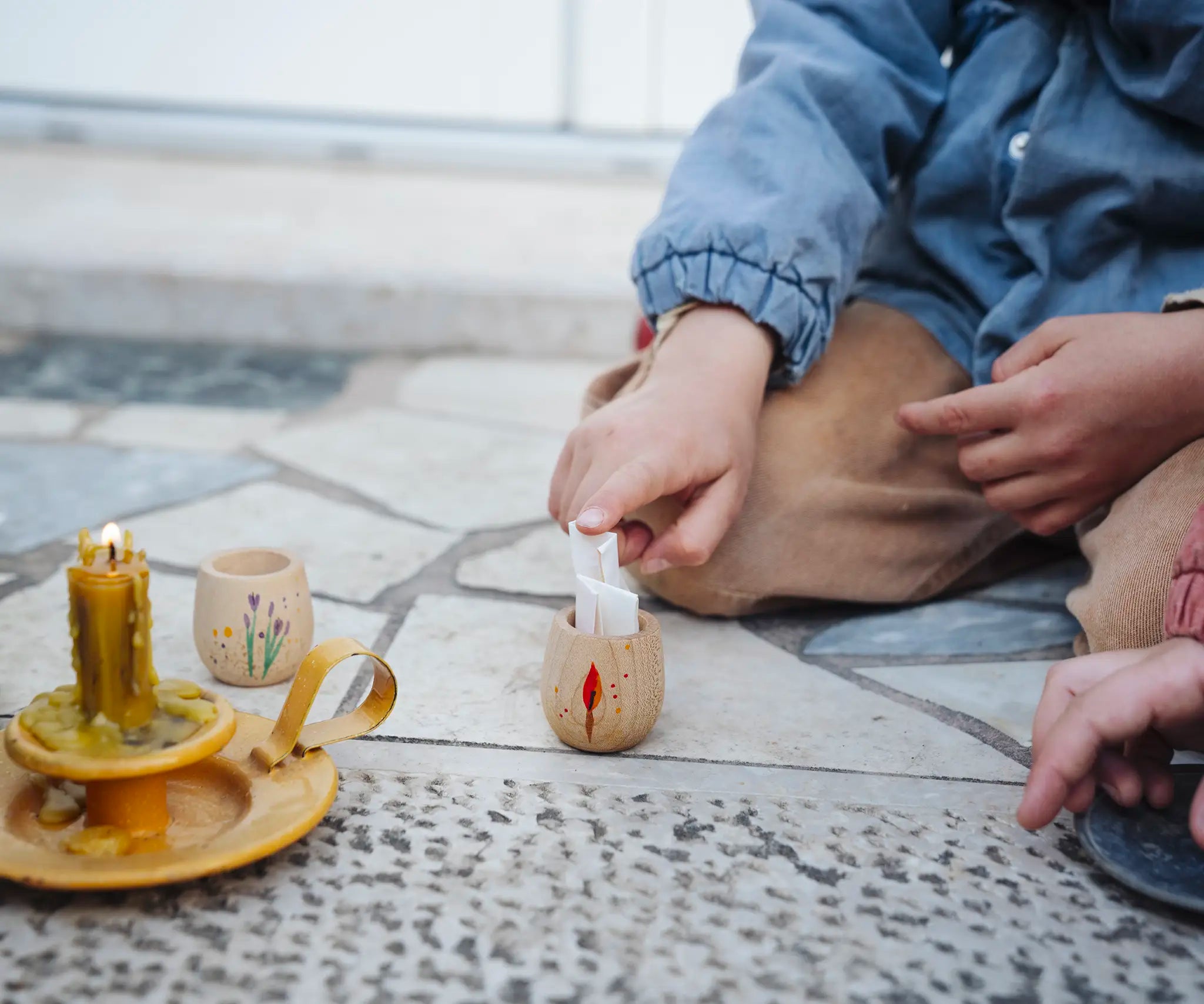 Child placing a piece of rolled up paper into a decorated wooden pot from one of the gifts included in the Grapat 2026 advent calendar available at Babipur. 