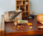 Wooden Tio log character with tangerine peel pieces placed ina  small wooden bowl. One of the gifts included in the Grapat 2026 advent calendar available at Babipur.