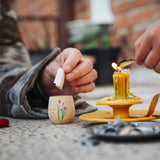 Child placing a piece of rolled up paper into a decorated wooden pot from one of the gifts included in the Grapat 2026 advent calendar available at Babipur. 