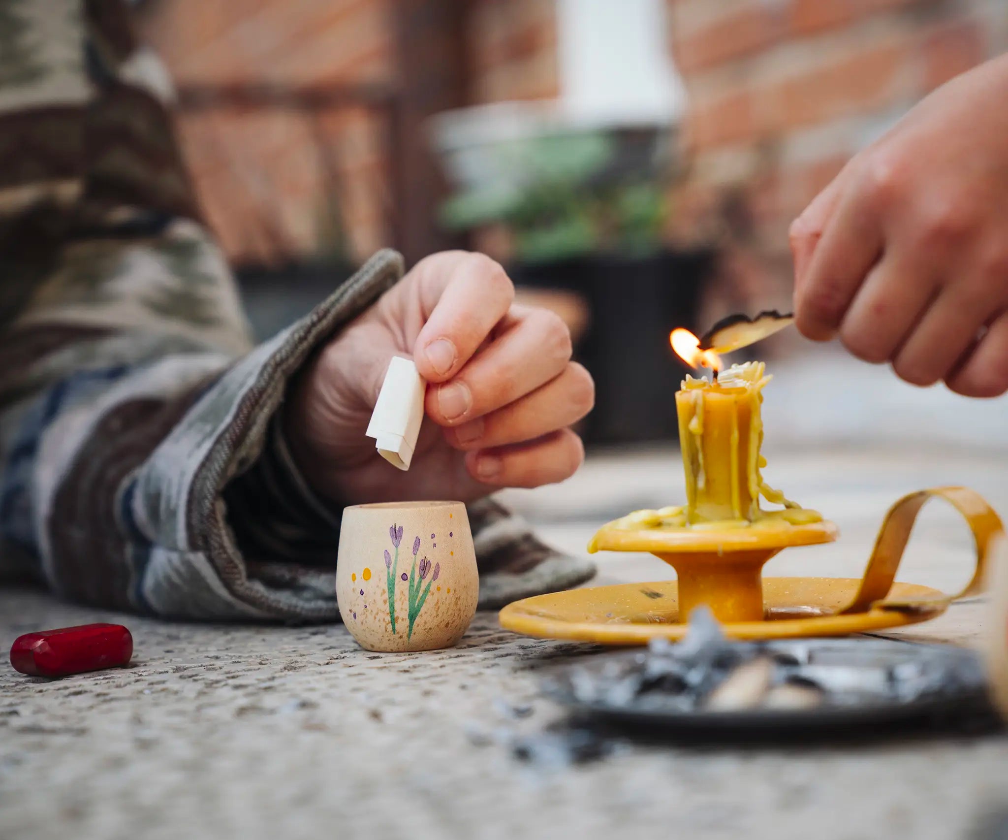 Child placing a piece of rolled up paper into a decorated wooden pot from one of the gifts included in the Grapat 2026 advent calendar available at Babipur. 