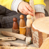 A close up of a child playing with the Grapat 3 Natural Nins. Three wooden peg dolls made from 3 different wood types. These wooden toys are part of a wide range of open ended toys available at Babipur.  