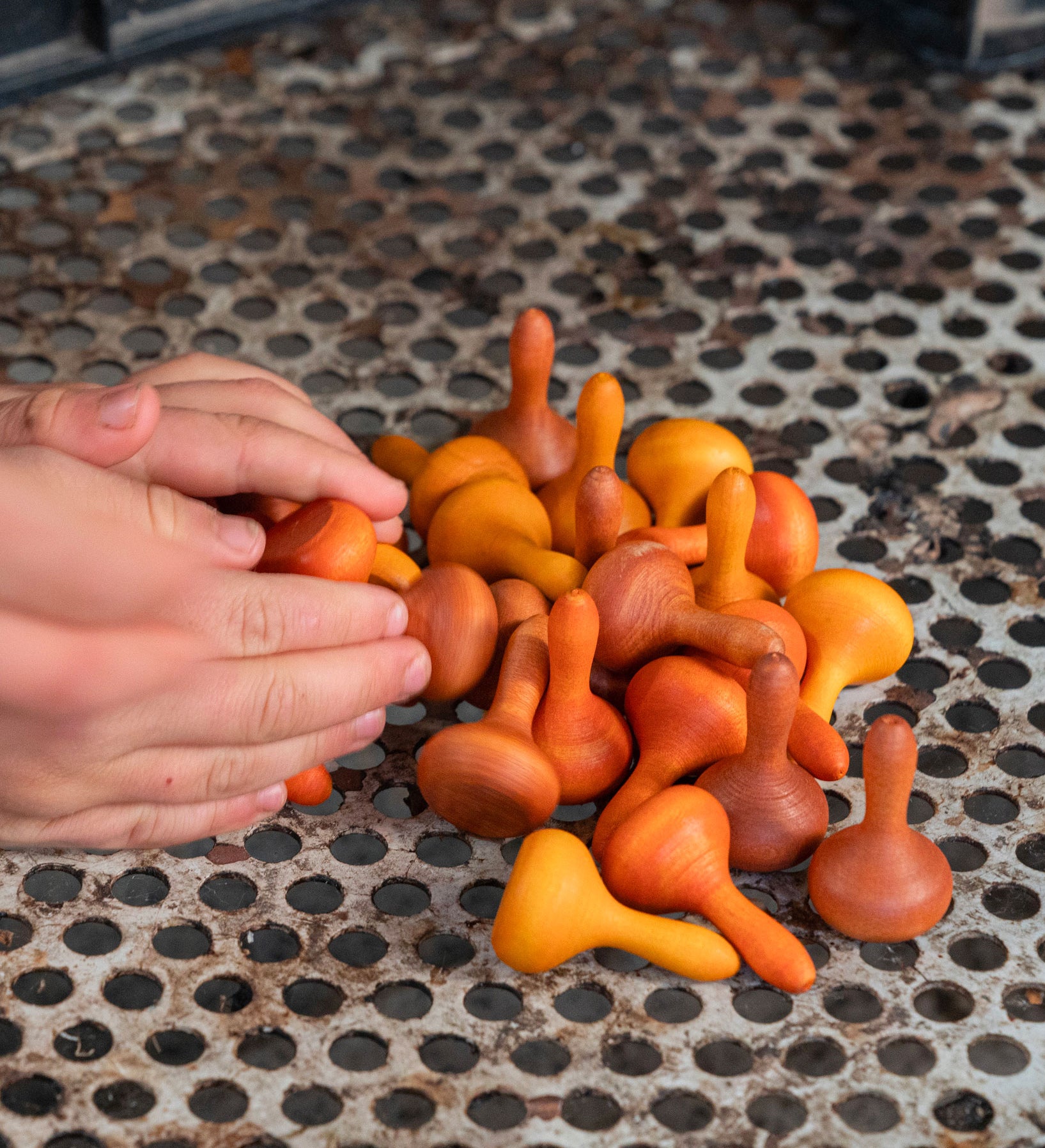 A hand reaching for the Grapat 36x Mandala Pumpkins in  shades of orange. 