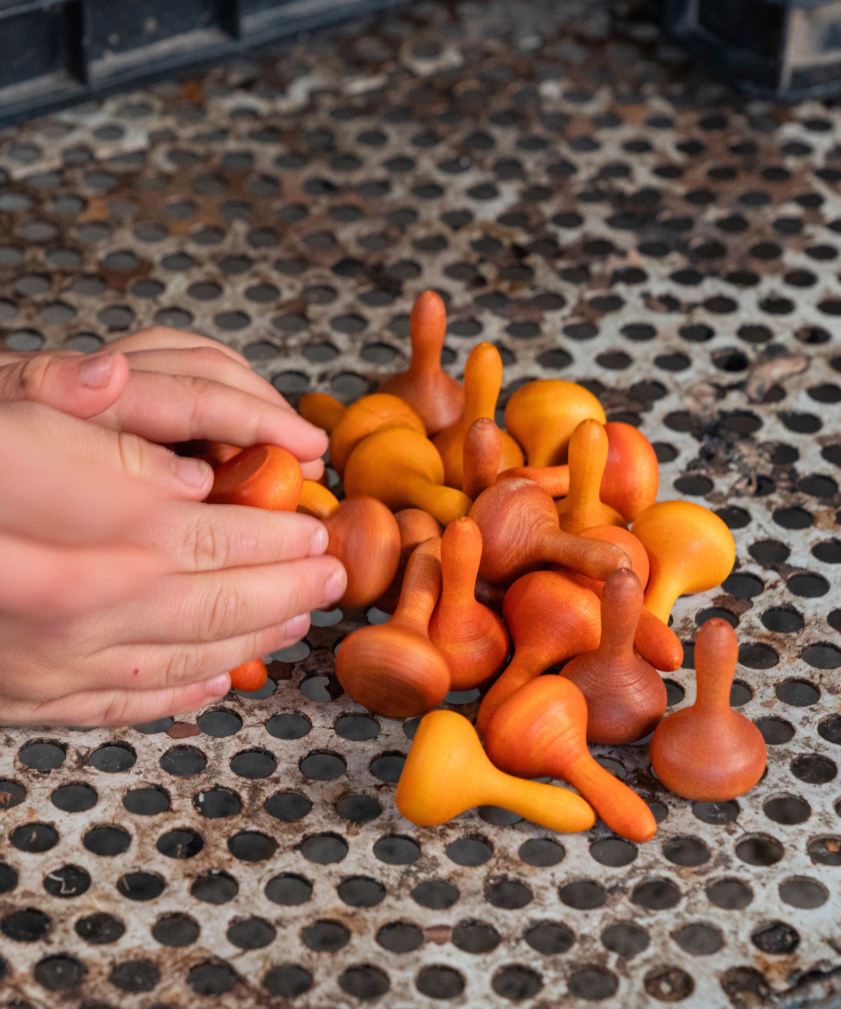 A hand reaching for the Grapat 36x Mandala Pumpkins in  shades of orange. 