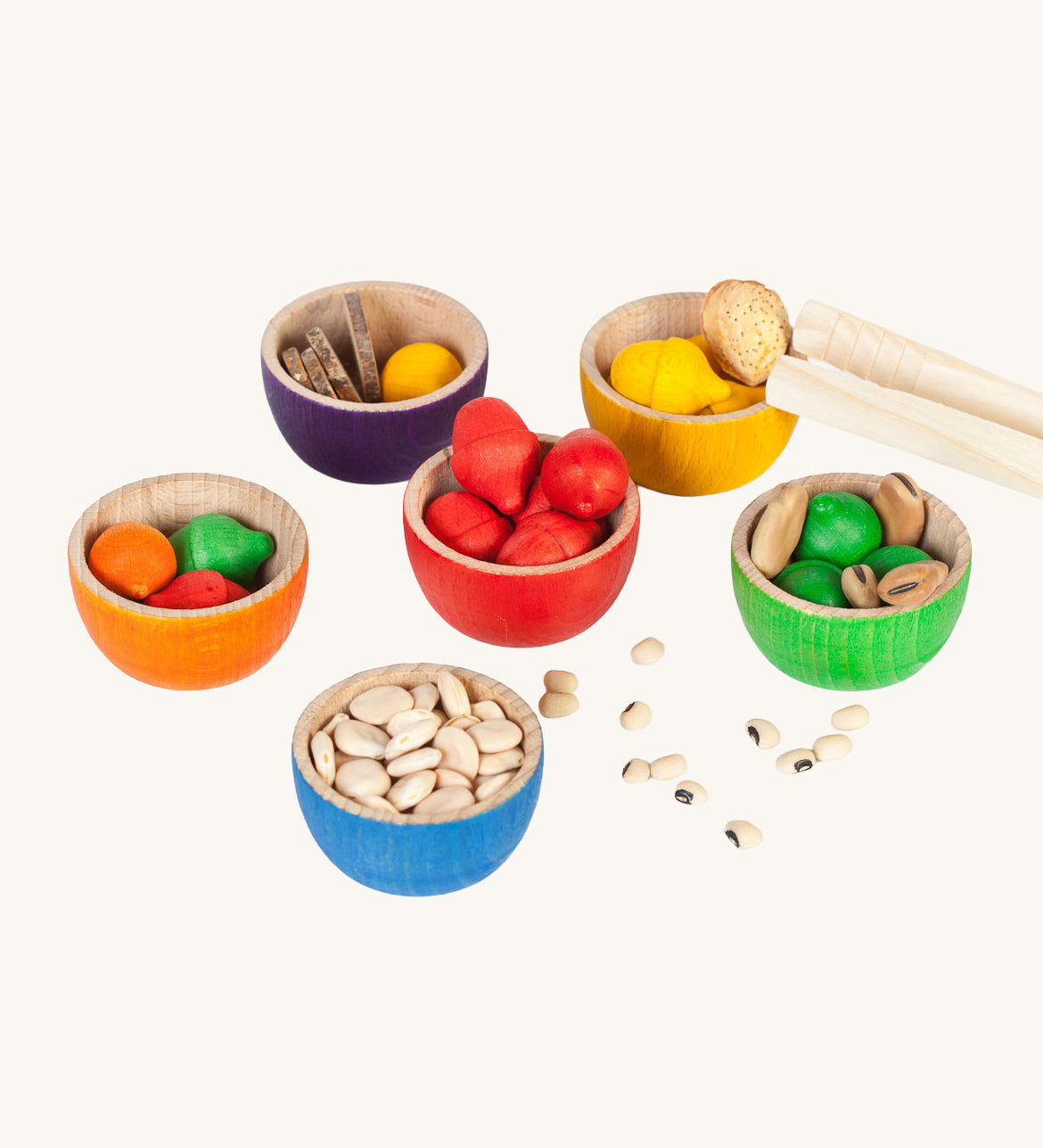Grapat 6 Rainbow Sorting Bowls filled up with Grapat acorns and dried beans and little wooden log slices. These wooden bowls are part of a wide range of loose parts and wooden toys available here at Babipur. 