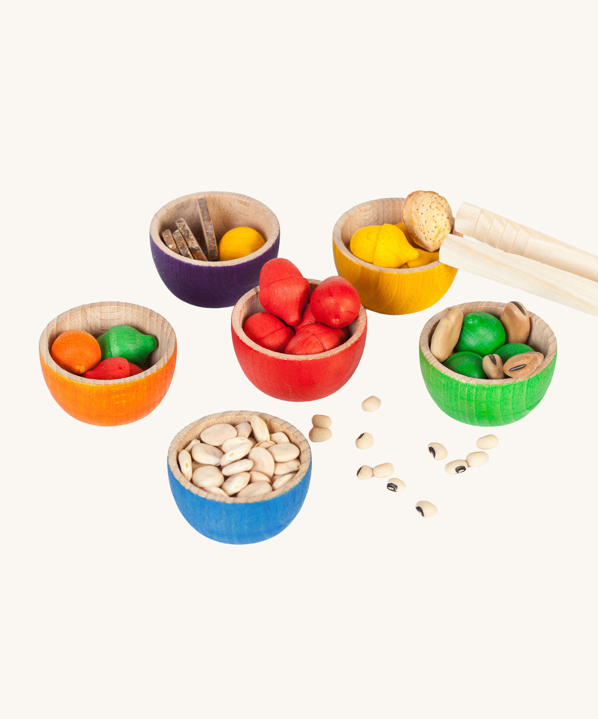 Grapat 6 Rainbow Sorting Bowls filled up with Grapat acorns and dried beans and little wooden log slices. These wooden bowls are part of a wide range of loose parts and wooden toys available here at Babipur. 