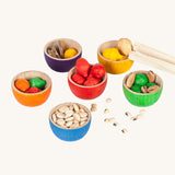 Grapat 6 Rainbow Sorting Bowls filled up with Grapat acorns and dried beans and little wooden log slices. These wooden bowls are part of a wide range of loose parts and wooden toys available here at Babipur. 