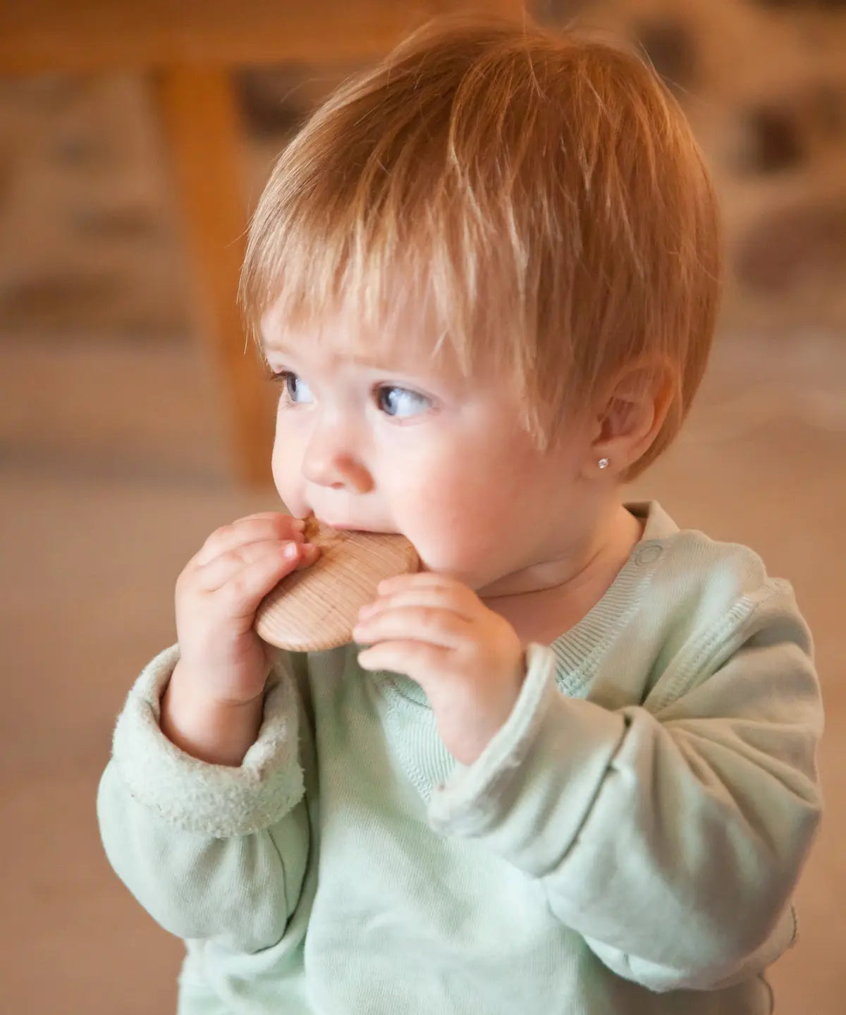 A child holding a Grapat wooden loose disk near the mouth