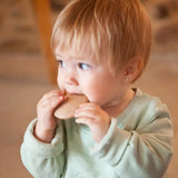 A child holding a Grapat wooden loose disk near the mouth