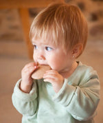 A child holding a Grapat wooden loose disk near the mouth