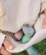 A close up of a child holding the  Grapat Handmade Wooden Aurora Eggs Cold Colours Easter Decorations in their jumper. 