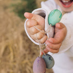 A close up of the Grapat Handmade Wooden Aurora Eggs Cold Colours Easter Decorations in a child's hand. 