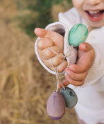A close up of the Grapat Handmade Wooden Aurora Eggs Cold Colours Easter Decorations in a child's hand. 