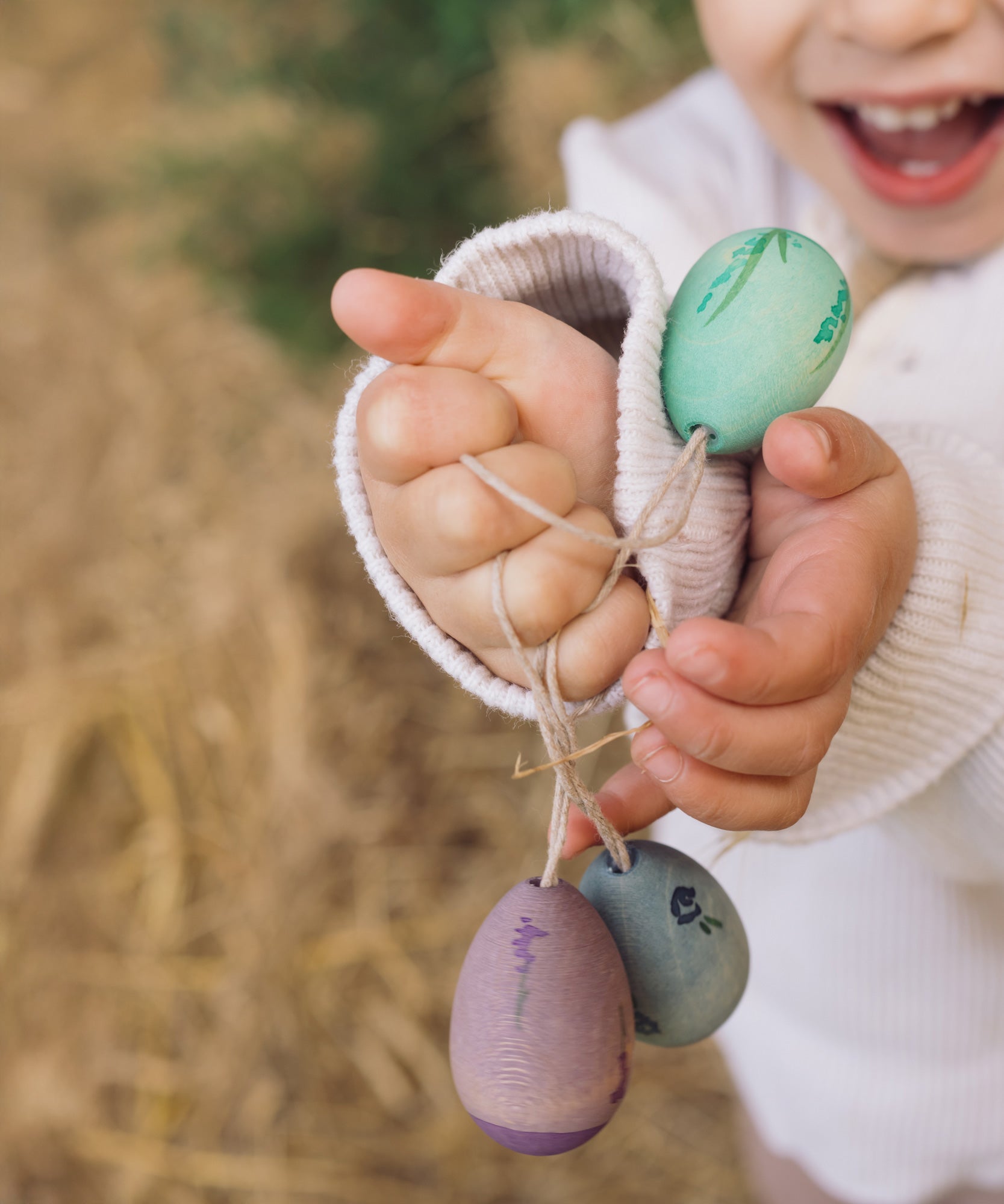 A close up of the Grapat Handmade Wooden Aurora Eggs Cold Colours Easter Decorations in a child's hand. 