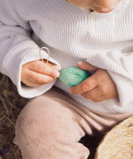 A close up of a green Grapat Handmade Wooden Aurora Egg decoration in a child's hands. 