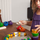 A child playing with the Grapat Wooden Toy Bowls and Marbles Set. A set of 6 coloured bowls with marbles in matching colours. These wooden toys are part of a wide range of open ended toys available at Babipur.  