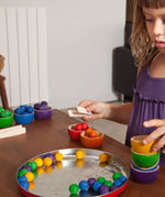 A child playing with the Grapat Wooden Toy Bowls and Marbles Set. A set of 6 coloured bowls with marbles in matching colours. These wooden toys are part of a wide range of open ended toys available at Babipur.  