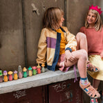 Close up of young boy leaning down to look at a plastic-free Grapat nini toy figure on the back of a red car