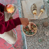 Close up of child's hands playing with the Grapat yummy wooden toy set on a metal bench