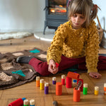 Child sat on the floor playing with the Grapat rainbow Lo stacking tubes