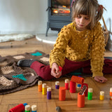 Child sat on the floor playing with the Grapat rainbow Lo stacking tubes