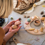 Close up of a child holding pieces of the Grapat Wonders toy set next to a perpetual ring calendar on a grey table cloth