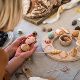 Close up of a child holding pieces of the Grapat Wonders toy set next to a perpetual ring calendar on a grey table cloth