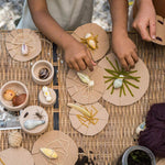 Close up of childrens hands doing crafts with the Grapat plastic-free wooden wild creature toys on a woven table