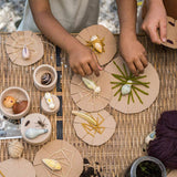 Close up of childrens hands doing crafts with the Grapat plastic-free wooden wild creature toys on a woven table